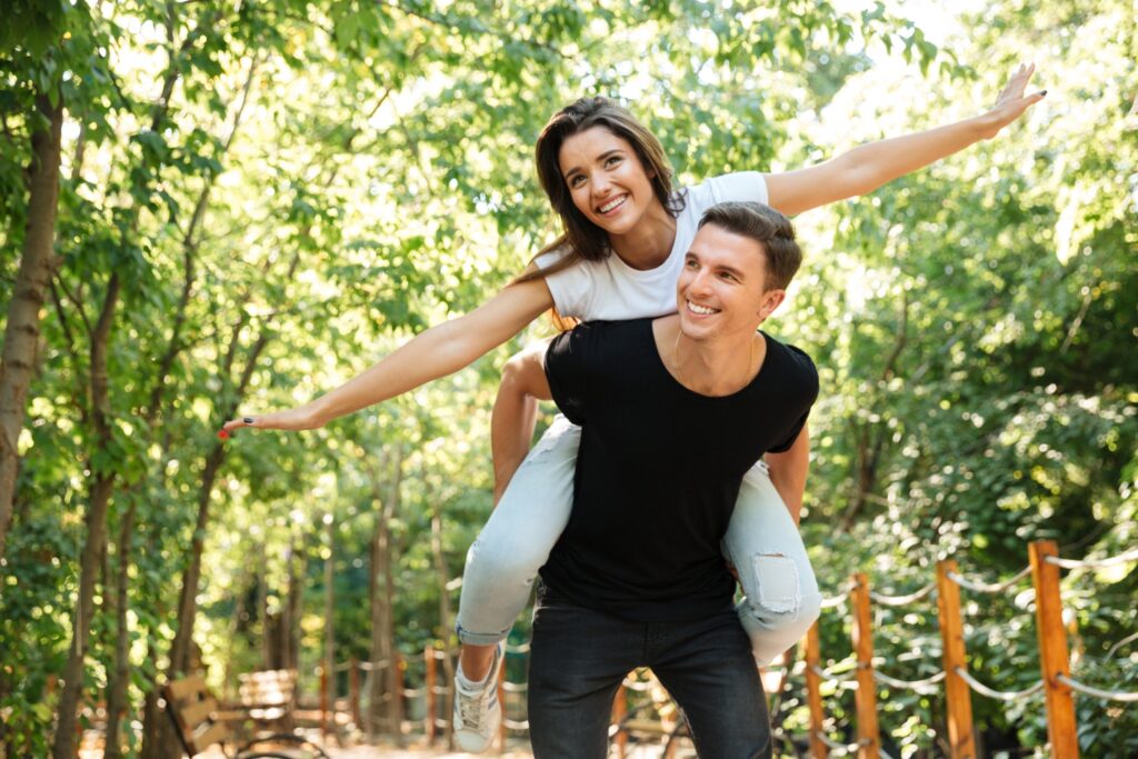 young smiling couple enjoying piggyback ride laughing